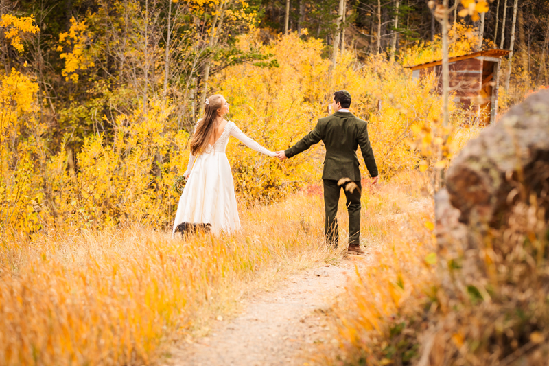 Elopement Photographer, a bride and groom walk on a golden country scale during the fall, they hold hands