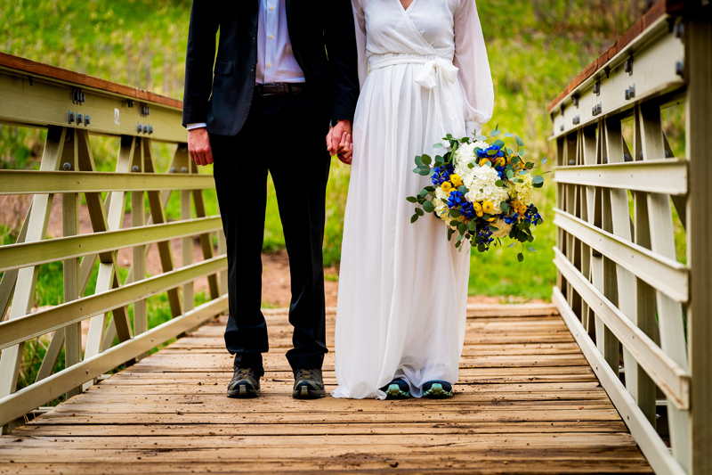Elopement Photographer, a bride and groom, in suit and dress, hold hands on a wooden country bridge in